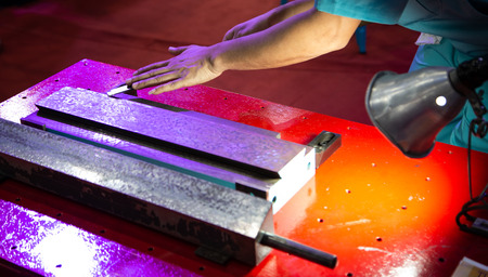Worker perform hand scraping slide way of the old bed machine