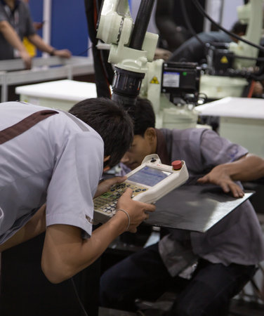 Bangkok, Thailand - May 10, 2019: Industrial technician operating robotic welding arm in Intermach...