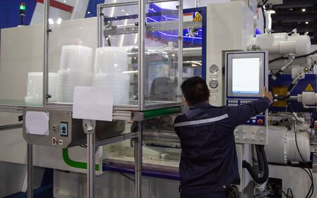 worker operating industrial plastic injection molding press machine for manufacturing