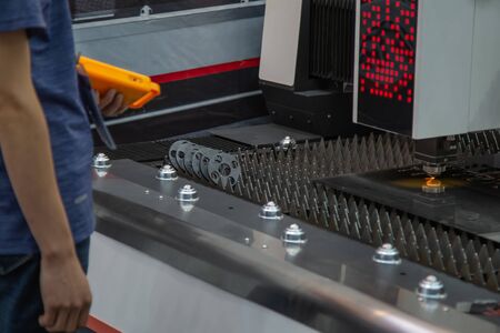 Industry worker operating laser cutting machine cutting metal sheet