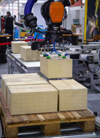 Industrial robot arm loading carton on conveyor in manufacturing production lineの写真素材