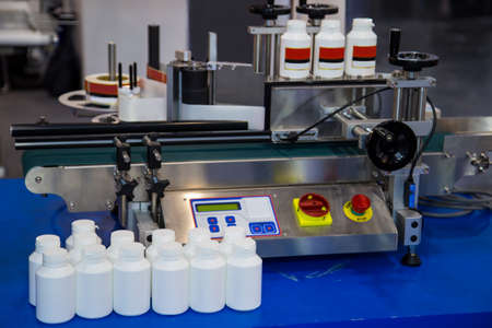 White plastic bottle on bottle labeling machine. Pharmaceutical industry