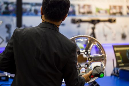 Industrial technician operating high technology portable 3D measurement scanner inspecting car wheelの写真素材