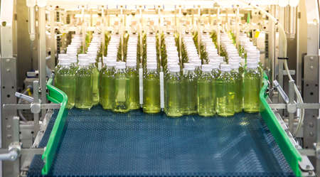 Conveyor with bottles for juice or water in factory interior of beverage plant.の写真素材