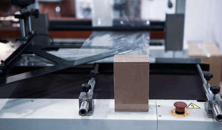 Shrink film package wrapping machine. Wrapping packaging of box. Industrial warehouse.の写真素材