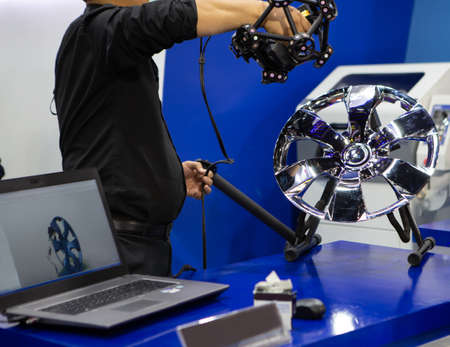 Industrial technician use handheld 3D scanner or portable CMM inspecting a wheel. Industrial...