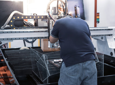 Industrial worker operate CNC fiber laser cutting machine. Industrial metalworking machinery