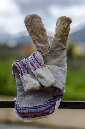 Victory hand sign by a worker's used gloveの写真素材