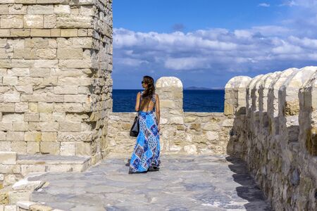 Heraklion City, Crete Island / Greece - October 26, 2017: Woman in blue dress enjoying the scenic view of the cretan sea from the roof of the fortress Koules on a warm sunny day with cloudy skyのeditorial素材