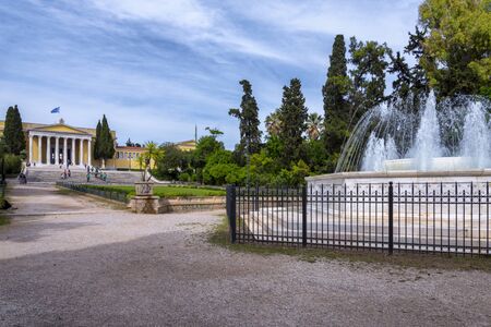 Athens City, Attica / Greece - May 20, 2019: Scenic view of the marble fountain gushing water and the Zappeion Hall neo-classical building in the National Garden park near Syntagma Square. Cloudy skyのeditorial素材