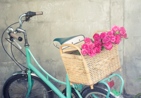 green retro bicycle with basket and rose flowers in back of the wall backgroundの写真素材