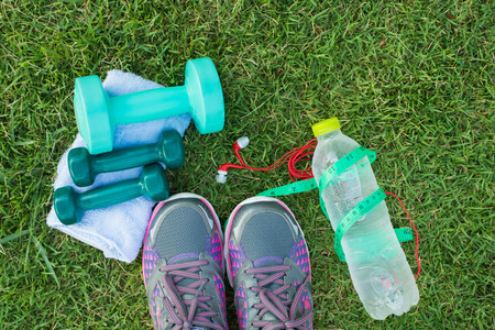 Healthy concept , diet plan with sport shoes and bottle of water and Dumbell on green grass backgroundの写真素材
