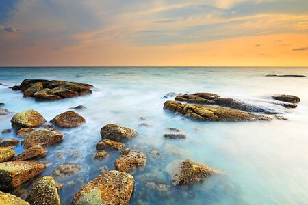 Beautiful seascape with sunset on the rocky shore of a tropical beach and Island