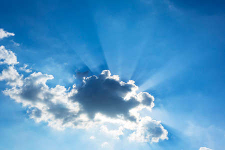 Sun rays through the clouds in the blue sky. Natural background.の写真素材