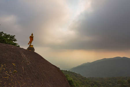 Golden buddha statue on the top of a mountain at sunsetの写真素材