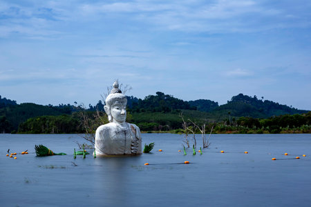 Long expousre of statue of Buddha in the middle of the water at the with at morning light abandoned temple at Khao Rakam Reservoir, Trat Province, Thailandの写真素材