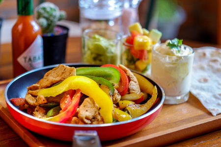 Mexican chicken fajitas in iron skillet with bell peppers and onionの写真素材