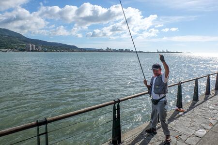 Taipei, Taiwan - July  16, 2018 : Tamsui fisherman fishing at shore of tamsui with landscape of bali and blue sky  background.のeditorial素材