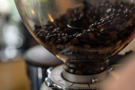 Coffee beans in the  machine grinder with bokeh background.