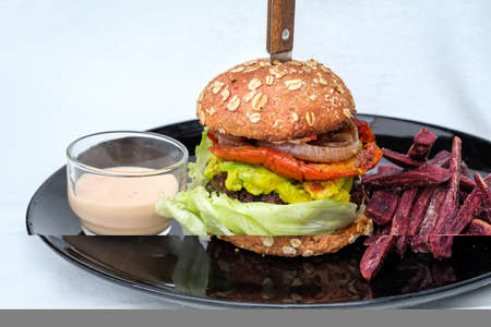 veggie, vegan burger with buckwheat, tomato, onion, vegan mayonnaise and spinach on a fresh bun with flax seeds and sesame,served with fried purple potatoの写真素材