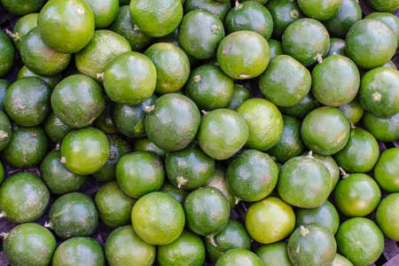 Background of fresh green limes closeup, on sale at local market.の写真素材