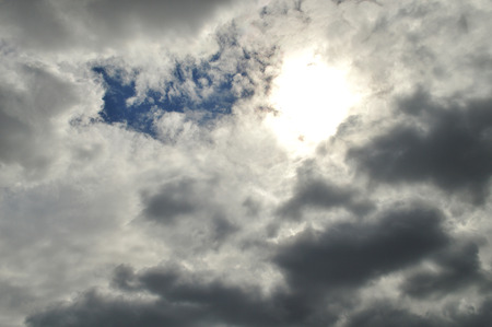 Grey clouds with a glimpse of the sky and the sun