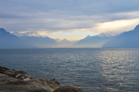Mountains and lake in cloudy weather, sun raysの写真素材
