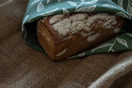 A loaf of bread on a bamboo board, sprinkled with oat flakes, in a burlap bagの写真素材