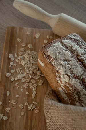 A loaf of bread on a bamboo board, sprinkled with oat flakes, in a burlap bagの写真素材