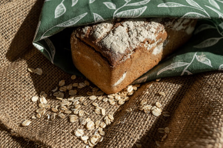 A loaf of bread on a bamboo board, sprinkled with oat flakes, in a burlap bagの写真素材