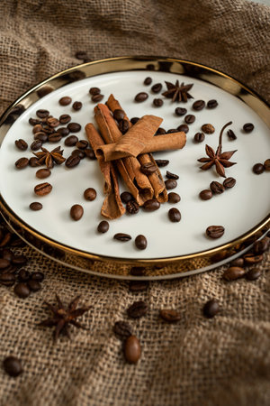 Spices cinnamon and anise on a golden plate, with coffee beans, a background of burlap. Rough texture and composition of spices. With dried flowers. It is used in confectionery, baの写真素材