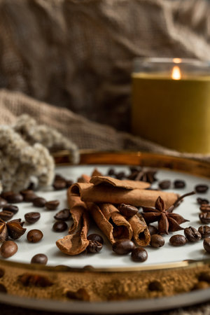 An elegant composition of candles, plates with a golden border, on which spices - anise, cinnamon...