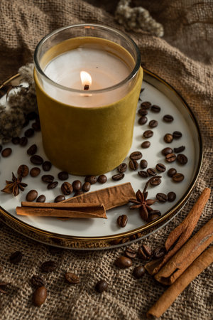 An elegant composition of candles, plates with a golden border, on which spices - anise, cinnamon and coffee beans lie. Against the background of burlapの写真素材