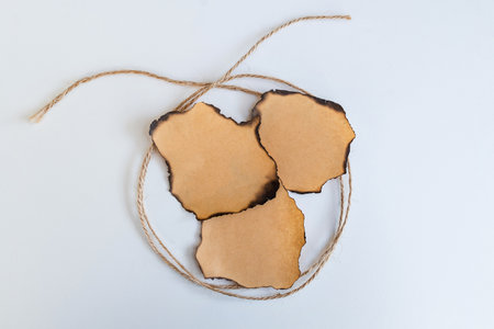 Rope bow and vintage paper pieces, charred edges, on a white backgroundの写真素材