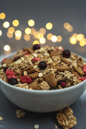 A bowl of muesli on a gray monochrome background, with white feathers and a side from a garland. Healthy food, healthy breakfastの写真素材
