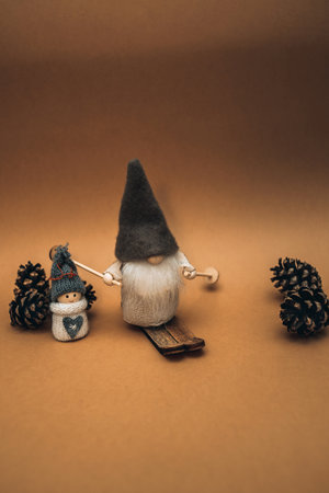 Cute dwarf, in a high copoak, on skis and a snowman on a brown background decorated with checkers....