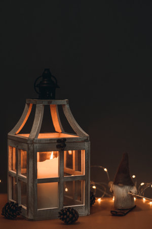 A cute dwarf, in a high hat, on skis and on a brown background, decorated with lanterns with a...