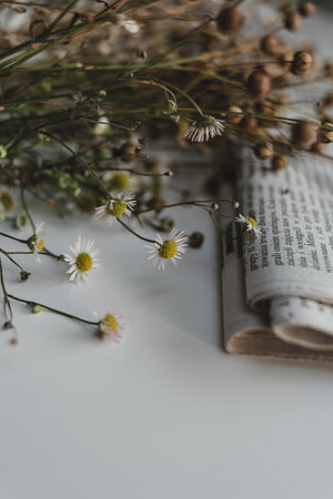A bouquet of dried wildflowers and a folded newspaper in retro style on a white background