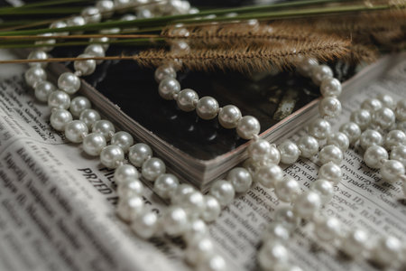 A string of pearls, a magazine and dried flowers lie on a newspaper, a photo in an elegant retro style.の写真素材