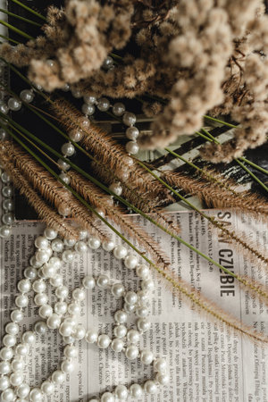 A string of pearls, a magazine and dried flowers lie on a newspaper, a photo in an elegant retro style.の写真素材