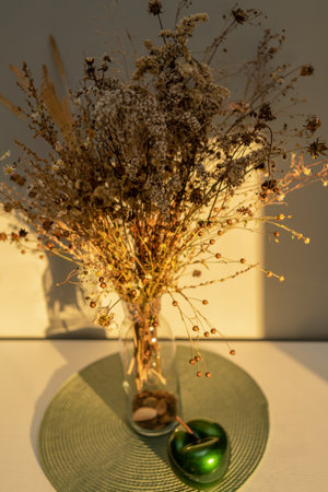 Bouquet of dried flowers on the table in a glass vase, in the light of the sun, contrasting image, with bright shadowsの写真素材