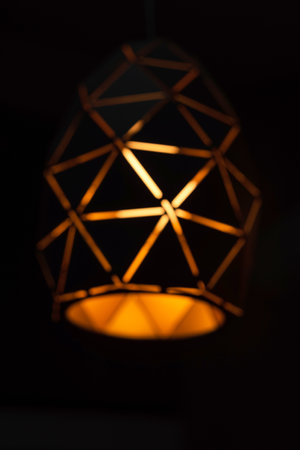 A blurred background of black lamps with a geometric pattern, three lamps on a black background, burning with warm light, with a graphic patternの写真素材