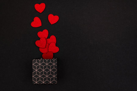 A gift box with a geometric pattern. Hearts in a gift box on a black background with a place for the...