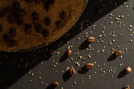 Coffee beans and cane sugar in a beam of light on a black paper backgroundの写真素材
