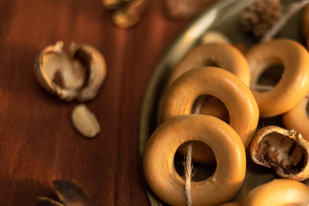 A bunch of bagels lie on a bronze platter, decorated with dried flowers and herbs. On a background...