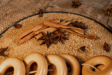 A bundle of mutton lies on cane sugar, next to spices - cinnamon sticks and anise stars. Against the background of coarse burlap. background for a pastry shop or grocery storeの写真素材