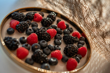 Raspberries and blackberries on a platter with a golden border. Healthy food on a plate.の写真素材