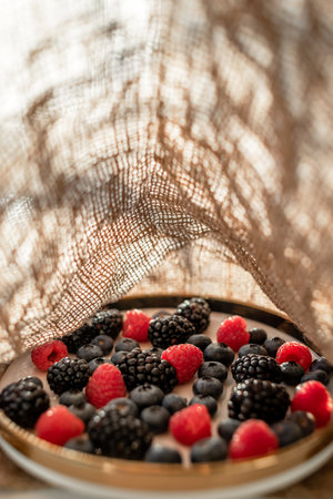 Raspberries and blackberries on a platter with a golden border. Healthy food on a plate.の写真素材
