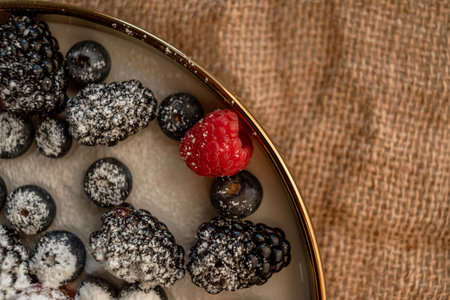 Raspberries and blackberries on a platter, sprinkled with powdered sugar. Healthy food on a plate