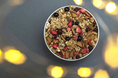 A bowl of muesli on a gray monochrome background, healthy food, healthy breakfast. With the glare of lights from the garlandの写真素材